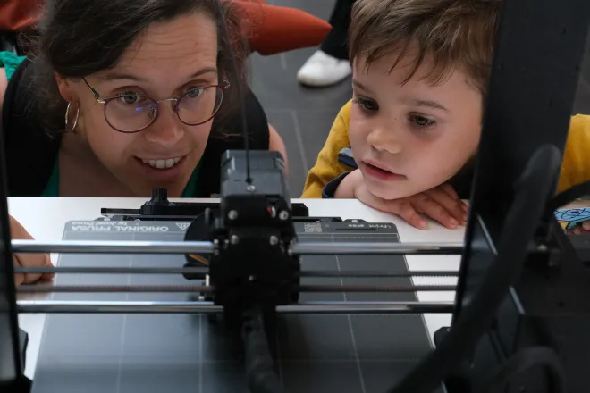 A mother and son looking at a 3D printer